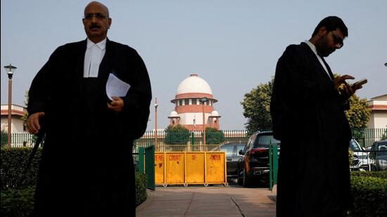 A lawyer looks into his mobile phone as another walks past, in front of the Supreme Court in New Delhi (REUTERS FILE PHOTO)