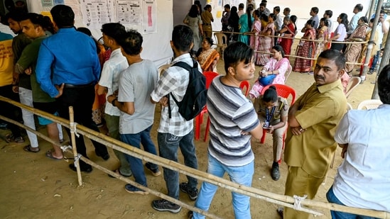 Voters stand in queues to cast their ballots to vote at a polling booth, during the Maharashtra state assembly elections.(AFP)