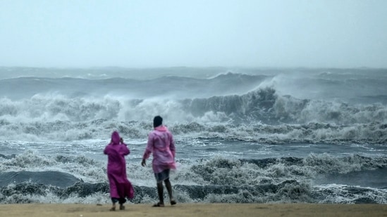 People stand ashore as they observe waves amidst heavy winds and rainfall at Marina Beach in Chennai on November 30, 2024, ahead of the landfall of cyclone Fengal in Tamil Nadu. (AFP)