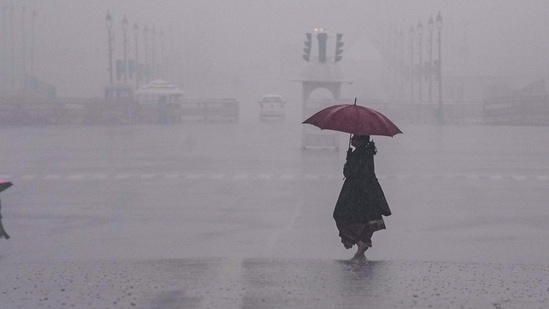 People move amid rain at Vijay Chowk, in New Delhi on Friday,(PTI) People move amid rain at Vijay Chowk, in New Delhi on Friday,(PTI)