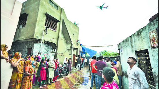 People wait for the funeral procession for Rajendra Patankar, a victim of the June 12 Air India plane crash, as a plane takes off from the airport in Ahmedabad, on Thursday. (AP) People wait for the funeral procession for Rajendra Patankar, a victim of the June 12 Air India plane crash, as a plane takes off from the airport in Ahmedabad, on Thursday. (AP)
